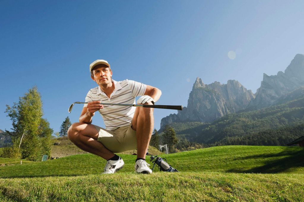 mid adult man squatting on golf course